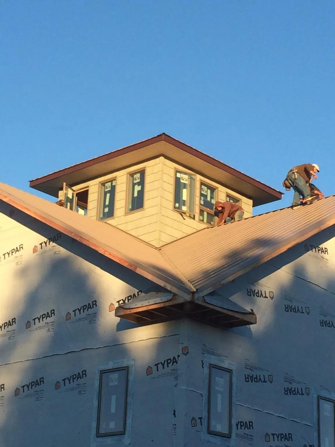 Roofers working around a rooftop cupola on a new metal roof at sunset — Roof Waterproofing in Bellwood by Roofing Brothers
